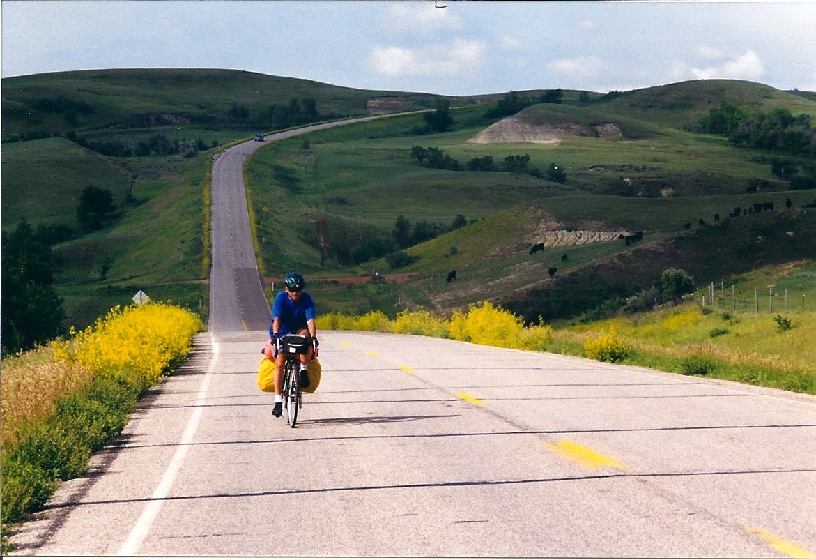 A loaded touring cyclist riding across North Dakota during the 1998 coast-to-coast tour.